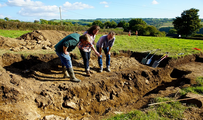 three people looking into a trench in the ground